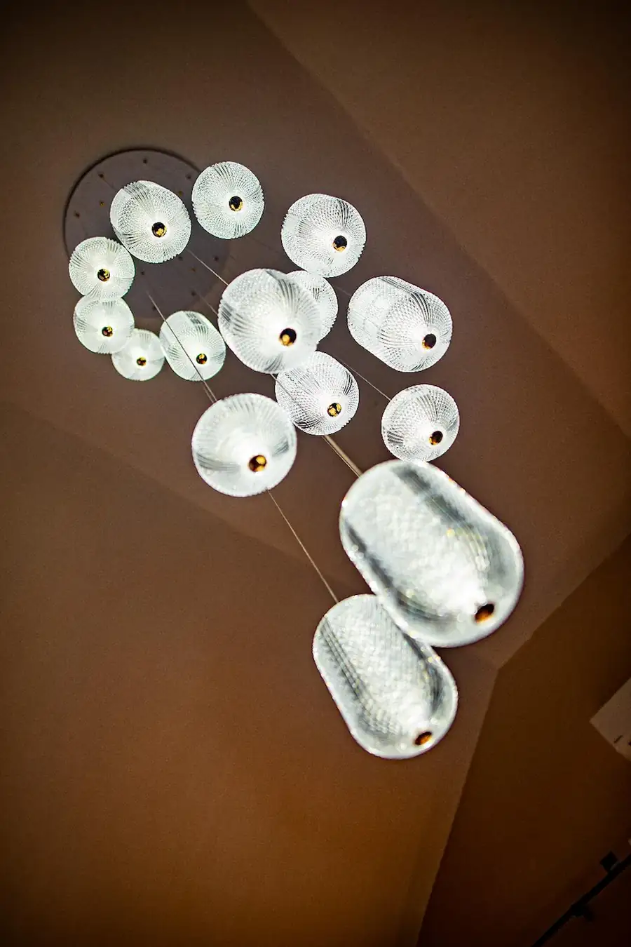 Detail view of a stunning multi-pendant glass chandelier hanging from the high ceiling in the Family Deluxe room at Turtle Seaweed Resort.
